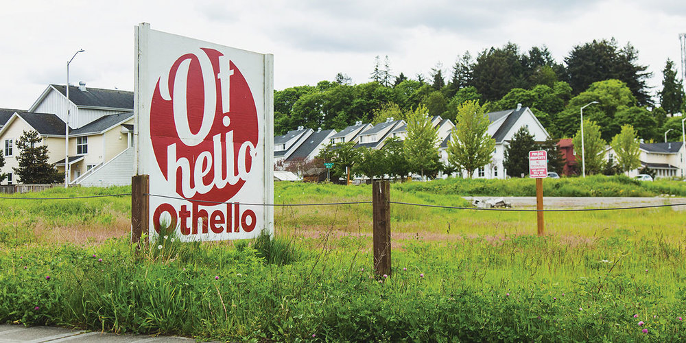 A grass field with homes in the background. There is a sign saying O! Othello Square.